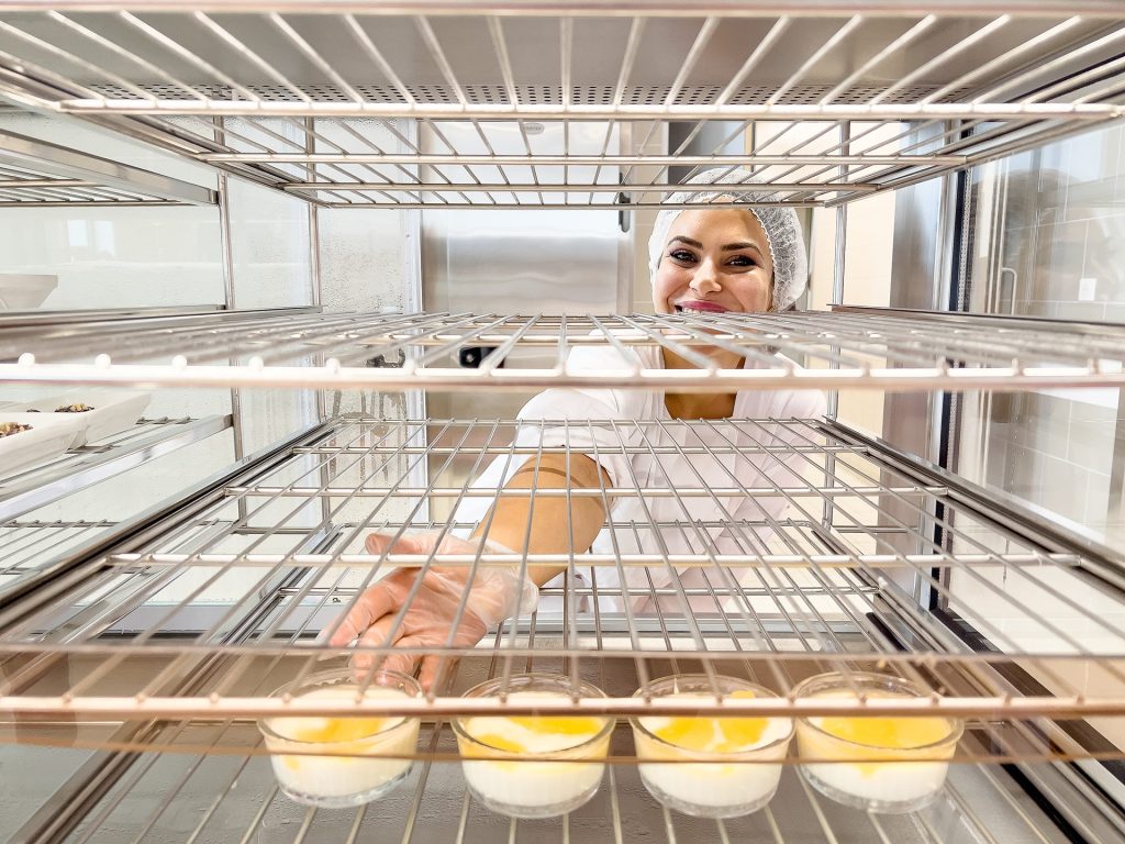 Agente de restauration scolaire qui pose un dessert sur une grille